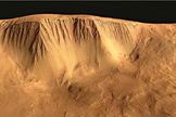 The western scarp of Olympus Mons has both steep and gentle slopes with clear channels, some likely created by flowing liquid, perhaps water, and some apparently carved by glaciers.