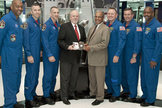 The STS-129 astronaut crew presents the space-flown flip coin to NFL officials at the Pro Football Hall of Fame on Jan. 27, 2010. The coin will decide the start of Super Bowl 44 in South Florida.