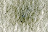 At the center of this view of an area of mid-latitude northern Mars, a fresh crater about 6 meters (20 feet) in diameter holds an exposure of bright material, blue in this false-color image.
