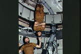 Astronaut Gerald P. Carr, commander for the Skylab 4 mission, jokingly demonstrates weight training in zero-gravity as he balances Astronaut William R. Pogue, pilot, upside down on his finger.