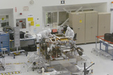 Technicians at NASA's Jet Propulsion Laboratory work on the Mars Science Laboratory rover Curiosity in May 2011. The rover is upside-down, and its six wheels are off (they rest on a table, at far right of the photo).