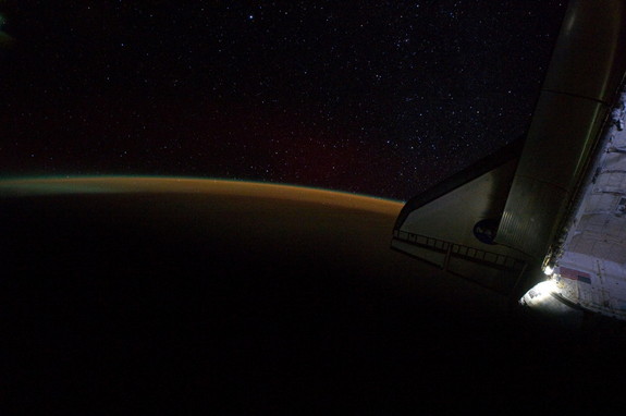 Earth's atmosphere and a starry sky just off the port wing of the docked space shuttle Endeavour are the subject of this image photographed by the Expedition 28 crew, while the shuttle was docked with space station on the STS-134 mission.