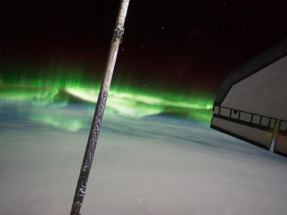 One of the STS-135 Atlantis crewmembers took this photo of the Southern Lights or Aurora Australis while visiting the International Space Station on July 14, 2011. Part of the orbiter boom sensor system (OBSS) is seen, as it was attached on the end of the shuttle's robotic arm (out of frame). A part of the port side wing of the shuttle is at right and a solar panel for the station is at left edge.