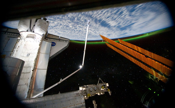 This panoramic view from the International Space Station, looking past the docked shuttle Atlantis' cargo bay and part of the station including a solar array panel toward Earth, was taken on July 14, 2011 as the spacecraft passed over the Southern Hemisphere. Aurora Australis or the Southern Lights can be seen on Earth's horizon and a number of stars are visible also.