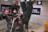 Made in Space team members with their 3-D printer hang on during a zero-g test flight.