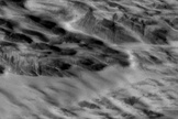 Martian terrain with dark streaks interpreted as avalanches blasted by shockwaves from a meteorite impact are visible in this photo from NASA's Mars Reconnaissance Orbiter.