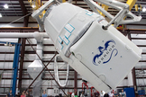 The Dragon spacecraft being rotated before it is mated to the Falcon 9 rocket in SpaceX’s hangar in Cape Canaveral, FL.