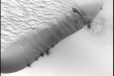 A comparison between a set of avalanches on a Martian dune and avalanches on a sand dune in Namibia. The Mars scale bar is 50 meters, indicating that the avalanches are all about 10 meters across, and the Namibia avalanches are about 30 centimeters wide, so the martian avalanches are about 30 times larger. Image added June 19, 2012.