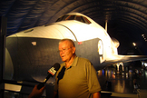 Fred Haise, Jr., veteran NASA astronaut, answers a reporter's questions with shuttle Enterprise in the background at the new Intrepid Museum exhibit. Photo taken July 18, 2012.