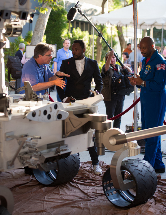 Musician Will.i.am, center, listens to NASA scientist Jim Garvin of the Goddard Space Flight Center talk next to a mock up of the Mars Science Laboratory rover Curiosity as astronaut Leland Melvin looks on at the Jet Propulsion Laboratory (JPL) a few hours ahead of the planned landing of the Curiosity rover on Mars, Sunday, Aug. 5, 2012 in Pasadena, Calif.