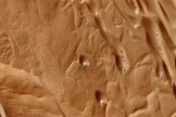 Avalanche in the northern polar region of Mars. On the left the avalanche creates a 180-foot-high dust cloud after falling nearly 2,000 feet from the scarp edge. To the right, black markings on frozen dunes give indications of a partial defrost. Photographed from an altitude of about 200 miles, the clarity of this view gives a clear indication of the spacecraft telescope's power. Mars Reconnaissance Orbiter, January 27, 2010.