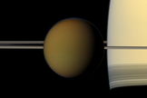 The colorful globe of Saturn's largest moon, Titan, passes in front of the planet and its rings in this true color snapshot from NASA's Cassini spacecraft. The north polar hood can be seen on Titan (3,200 miles or 5,150 kilometers across) and appears as a detached layer at the top of the moon here. Image released Dec. 22, 2011.