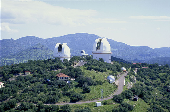 The two large domes in the foreground house the 2.1-meter (82-inch) Otto Struve Telescope (left) and the 2.7-meter (107-inch) Harlan J. Smith Telescope (right). Between these two, the Hobby-Eberly Telescope (HET) can be seen, atop neighboring Mt. Fowlkes