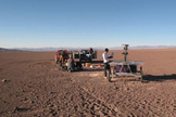 The Zoë rover being checked out at the start of its Atacama Desert traverse in June 2013. In the background are the two 4x4 trucks that were used to follow the robot. The engineers stay within communication range to monitor the robot but try to say out of view as much as possible.