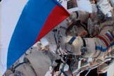 A cosmonaut holds a Russian flag during a spacewalk outside the International Space Station in honor of Russian Flag Day on Aug. 22, 2013.