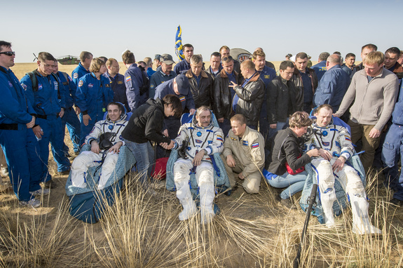 Expedition 36 Flight Engineer Chris Cassidy of NASA, left, Commander Pavel Vinogradov of the Russian Federal Space Agency (Roscosmos), center, and, Flight Engineer Alexander Misurkin of Roscosmos, sit in chairs outside the Soyuz TMA-08M capsule just minutes after they landed in a remote area near the town of Zhezkazgan, Kazakhstan, on Wednesday, Sept. 11, 2013. Vinogradov, Misurkin and Cassidy returned to Earth after five and a half months on the International Space Station.