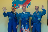 Expedition 37 NASA Flight Engineer Michael Hopkins, far left, Soyuz Commander Oleg Kotov and Russian Flight Engineer Sergey Ryazanskiy, far right, wave and give the thumbs up following a press conference held at the Cosmonaut Hotel, on Tuesday, Sept. 24, 2013, in Baikonur, Kazakhstan.