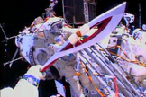 The Olympic torch is seen from the helmet camera of Russian cosmonaut Oleg Kotov in this view from a spacewalk on Nov. 9, 2013. Cosmonaut Sergey Ryazanskiy is seen awaiting the torch, which will be used in the 2014 Winter Games in Sochi, Russia.
