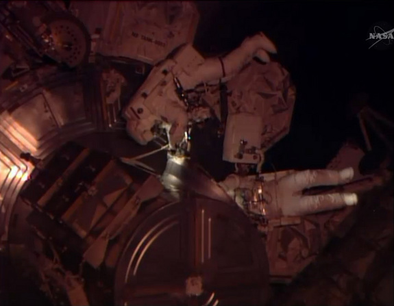 NASA astronaut Rick Mastracchio (center) floats above the Quest airlock outside the International Space Station while crewmate Steve Swanson (partially obscured) is nearby during a computer repair spacewalk on April 23, 2014.
