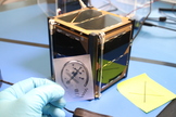 This image of the ISO Logo engraved on a Nanosatisfi satellite was taken by Nelly Ben Hayoun.