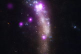 A composite image of the supernova SN 2010jl within its galaxy shows X-ray observations from the Chandra X-ray Observatory (in purple) and optical data from the Hubble Space Telescope. SN 2010jl appears as the bright purple spot at the top of the galaxy.