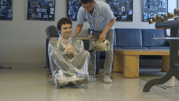 Science educator Tien Huynh-Dinh at the LIGO Science Education Center vacuum-wraps audio engineer Joe Chilcott in a demonstration of the atmospheric pressure humans live with, every day, on this planet at the LIGO Observatory in Livingston, Louisiana.