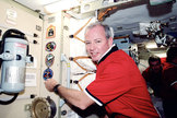 STS-92 commander Brian Duffy adds the patch for the 100th space shuttle mission to the International Space Station's wall in 2000.