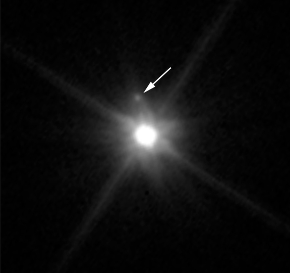 This photo by NASA’s Hubble Space Telescope reveals the first moon ever discovered around the dwarf planet Makemake. The 100-mile-wide (160 kilometers) satellite is barely visible just above Makemake, almost lost in the glare of the bright dwarf planet.