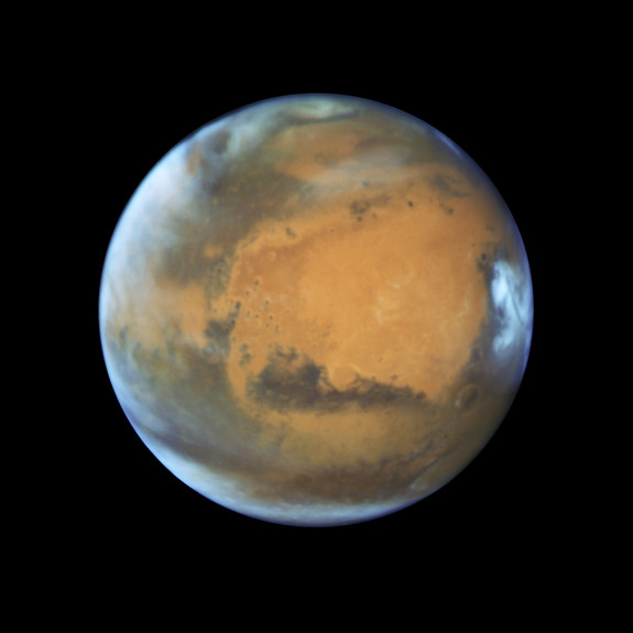 Mars as it was observed shortly before opposition in May 2016 by the Hubble Space Telescope. Some prominent features are clearly visible, including the heavily eroded Arabia Terra in the center of the image and the small southern polar cap.