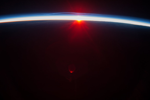Photo taken by astronauts of noctilucent clouds in Earth’s atmosphere above the midnight sun (above the blue layer).