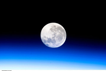 A full moon is visible in this view above Earth's horizon and airglow, photographed by Expedition 10 Commander Leroy Chiao on the International Space Station.